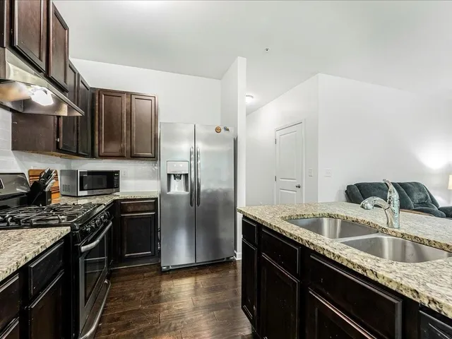 a kitchen with stainless steel appliances granite countertop a sink a stove and a refrigerator
