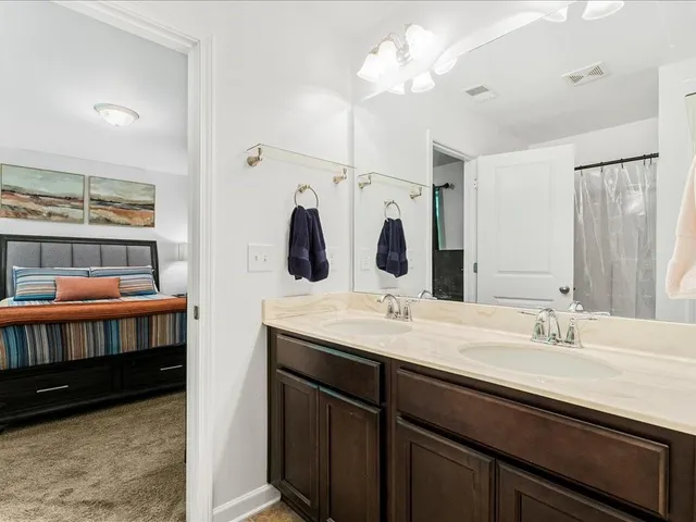 a en suite bathroom with a double vanity sink a mirror and shower