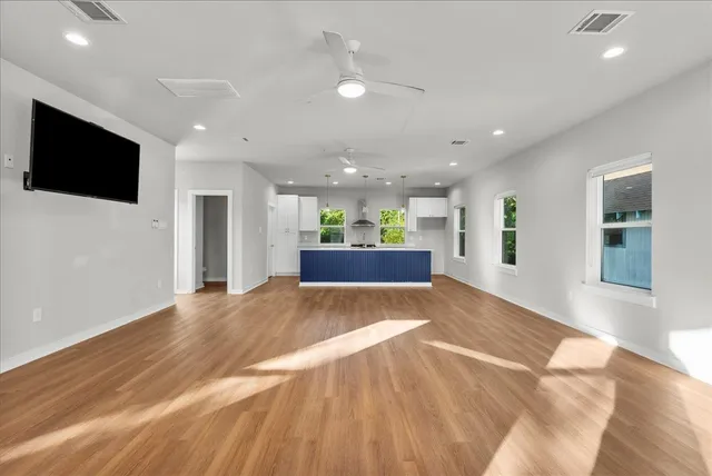 a view of an empty room with kitchen and a window