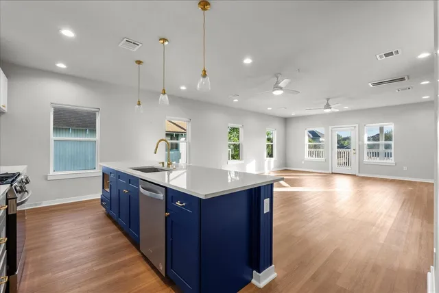 a kitchen with stainless steel appliances granite countertop a sink a stove and a wooden floors
