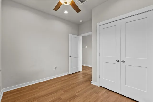 an empty room with wooden floor and ceiling fan