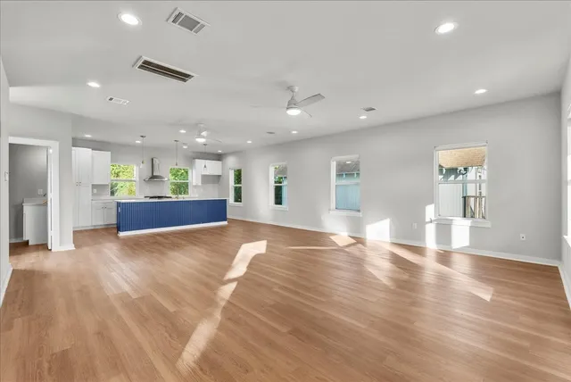 a view of an empty room with kitchen and a window