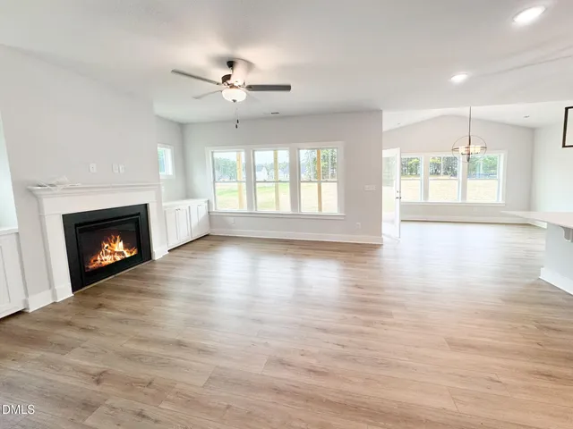 a view of an empty room with wooden floor and a fireplace