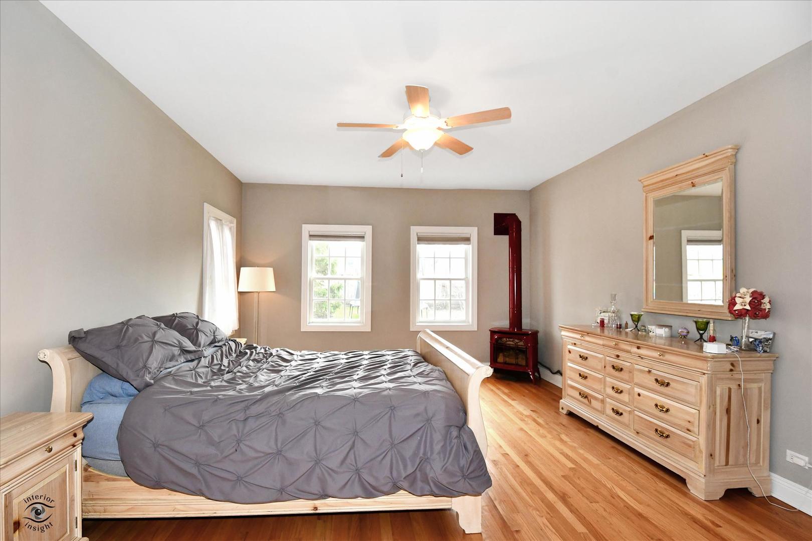 617 Hillside Road Glenview, IL 60025 - Photo 14 of 46 a spacious bedroom with a bed a dresser and a chandelier
