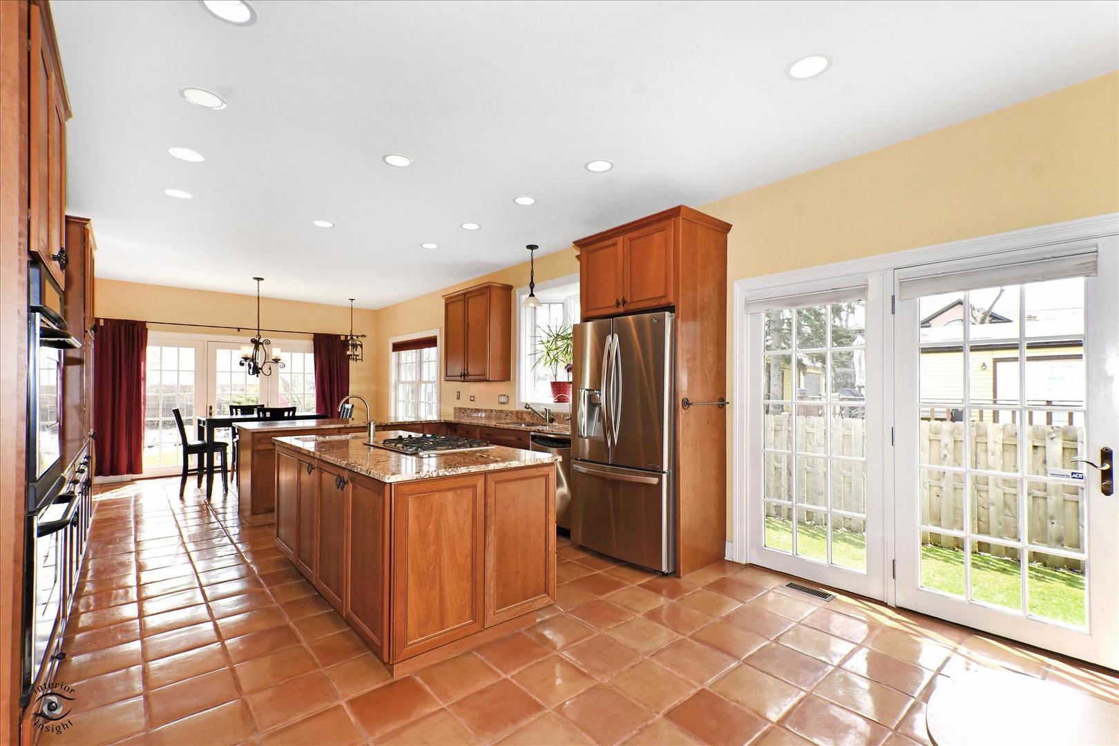 617 Hillside Road Glenview, IL 60025 - Photo 9 of 46 a kitchen with stainless steel appliances granite countertop a refrigerator a sink a stove top oven and a dining table with wooden floor