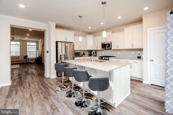 a kitchen with kitchen island stainless steel appliances a sink a stove a refrigerator and cabinets