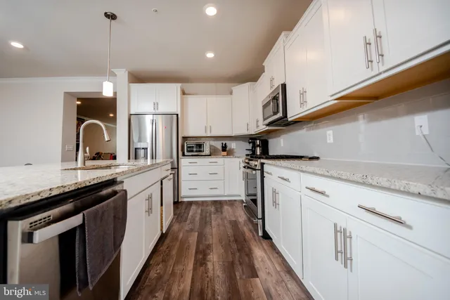 a kitchen with stainless steel appliances granite countertop a sink a stove and refrigerator