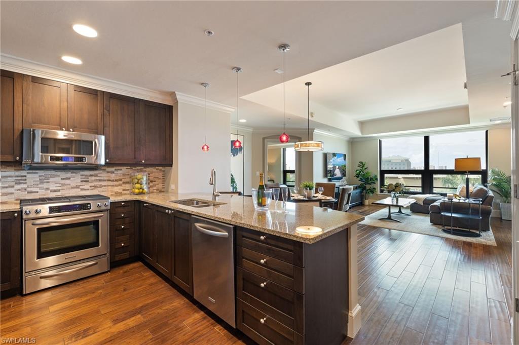 9115 Strada Place, Unit 5506 Naples, FL 34108 - Photo 45 of 46 Kitchen featuring appliances with stainless steel finishes, dark wood finished floors, open floor plan, a peninsula, and light stone countertops