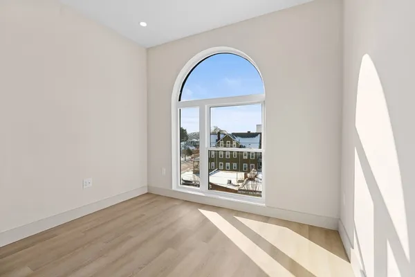 an empty room with wooden floor and a floor to ceiling window