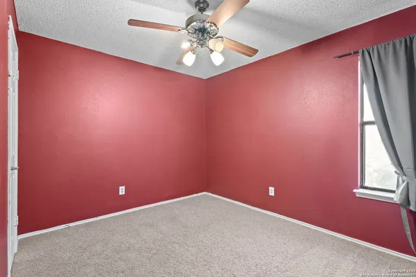 an empty room with windows and ceiling fan