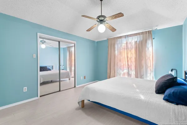 a bedroom with a large bed and a chandelier fan