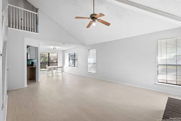 an empty room with chandelier fan and windows