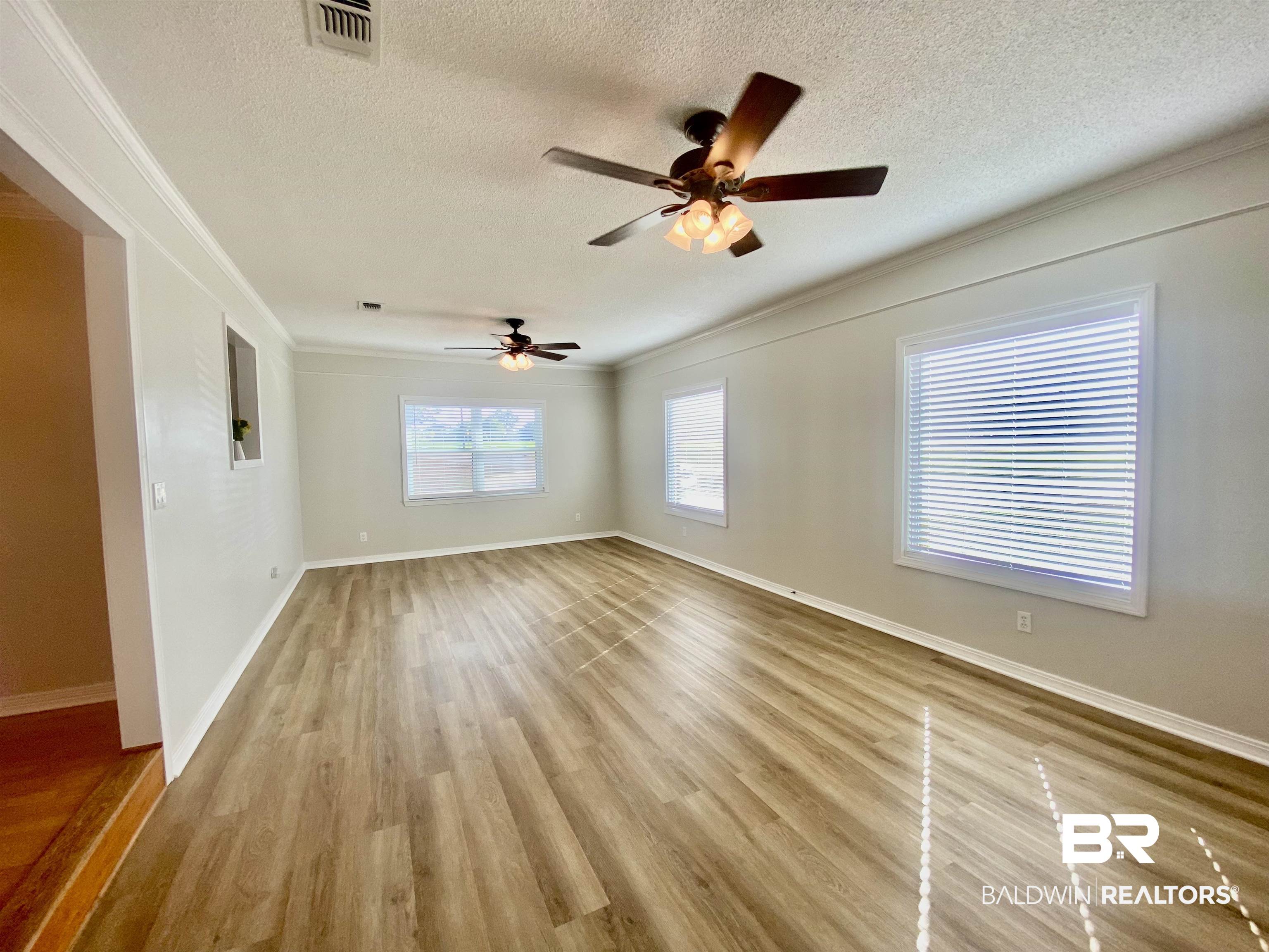 265 Azalea Drive Monroeville, AL 36460 - Photo 13 of 39 Unfurnished room featuring crown molding, a textured ceiling, ceiling fan, and light hardwood / wood-style flooring