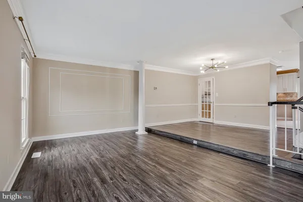 a view of an empty room with window and wooden floor