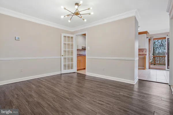 an empty room with wooden floor staircase and windows