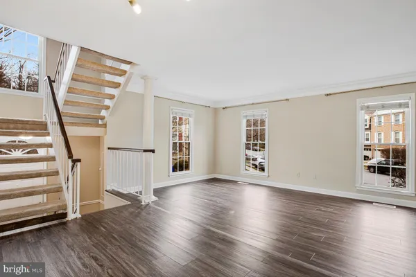 a view of an empty room with wooden floor and windows