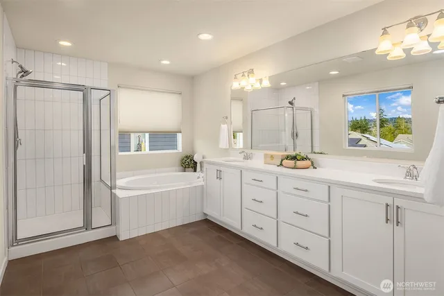 a spacious bathroom with a double vanity sink a mirror a shower and a bathtub