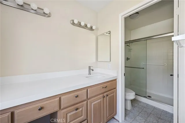 a bathroom with a granite countertop sink a toilet and shower