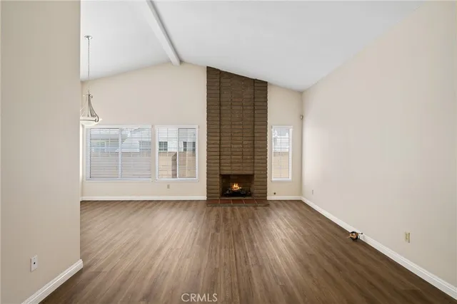 a view of an empty room with wooden floor fireplace and a window