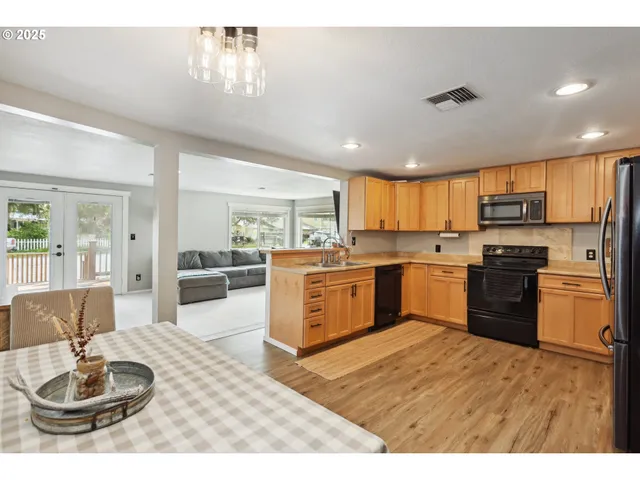 a kitchen with a refrigerator a stove top oven a sink dishwasher and white cabinets with wooden floor