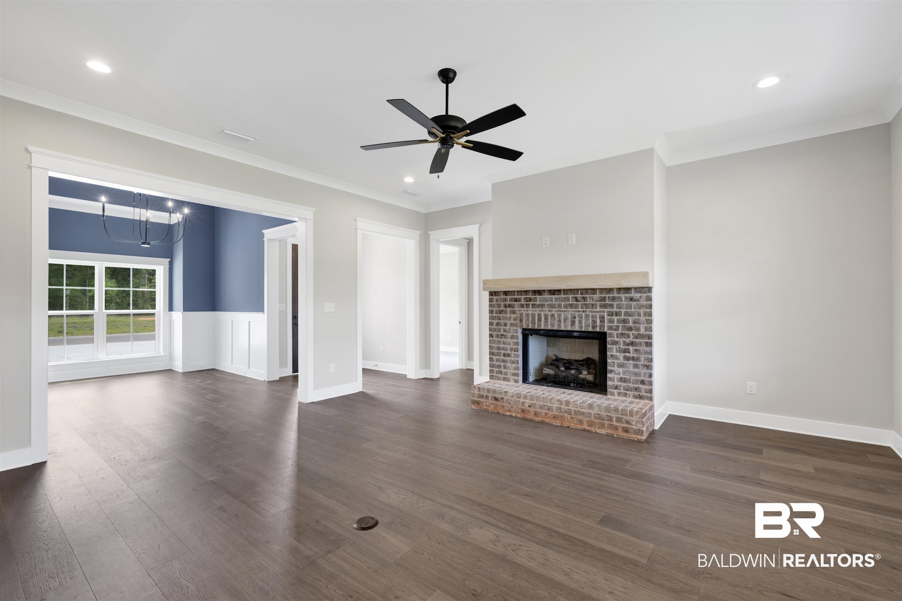 27315 Patch Pl Loop Daphne, AL 36526 - Photo 10 of 43 Unfurnished living room with ceiling fan, a fireplace, ornamental molding, hanging lights, and wood flooring