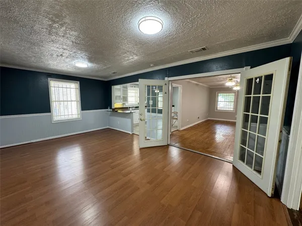 an empty room with wooden floor and entrance to ceiling window