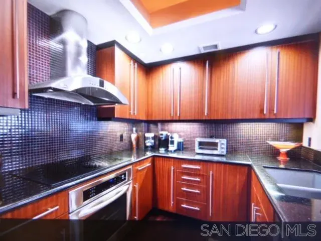 a kitchen with granite countertop stainless steel appliances a sink a stove and cabinets