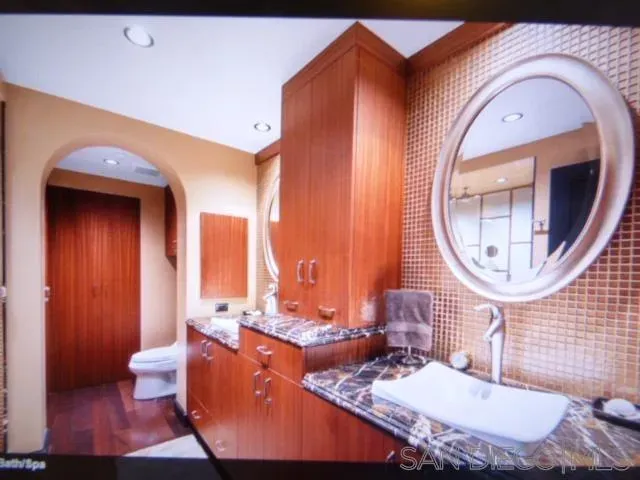 a bathroom with a granite countertop toilet a sink and a mirror