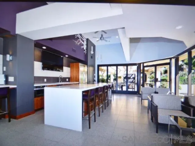 a living room with stainless steel appliances furniture a flat screen tv and a kitchen view