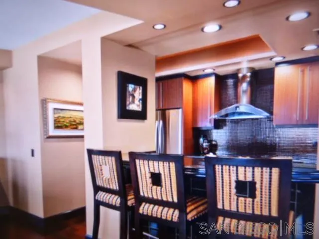 100 Harbor Drive, Unit 3404 San Diego, CA 92101 - Photo 10 of 30 a kitchen with stainless steel appliances granite countertop a stove a refrigerator a sink a dining table and chairs with wooden floor