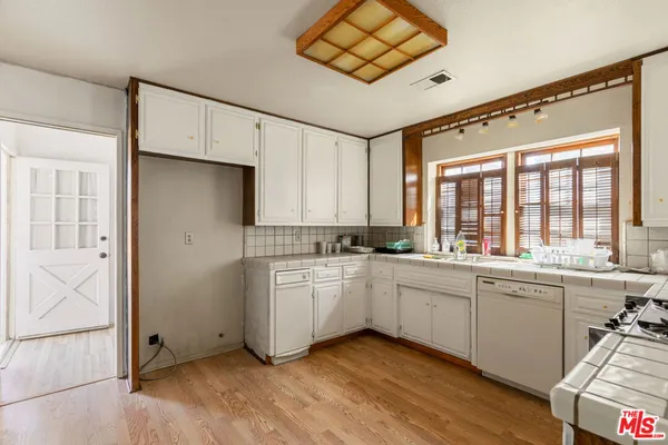 a large white kitchen with a large window appliances and furniture