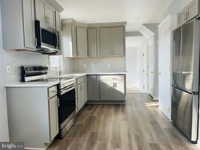 a kitchen with stainless steel appliances granite countertop a stove top oven a refrigerator a sink and dishwasher with wooden floor