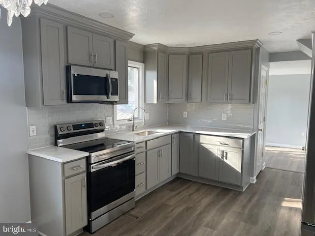 a kitchen with cabinets stainless steel appliances and wooden floor