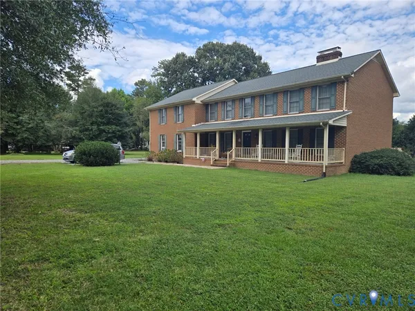 a view of a house next to a big yard and large trees