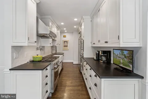 a kitchen with stainless steel appliances a stove top oven a sink a counter space and cabinets