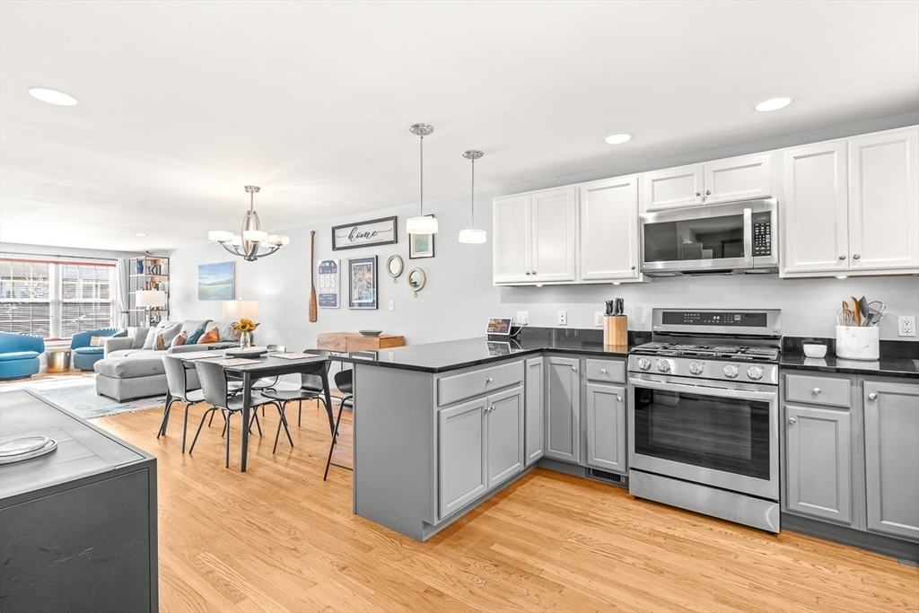 77 Warren Street, Unit A Arlington, MA 02474 - Photo 8 of 34 a kitchen with stainless steel appliances kitchen island granite countertop a stove top oven a sink a dining table and chairs with wooden floor