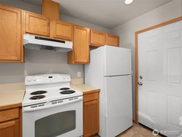 a white refrigerator freezer and a stove sitting inside of a kitchen