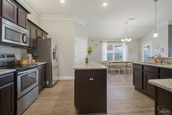 a kitchen with stainless steel appliances granite countertop a stove top oven a sink dishwasher and a dining table with wooden floor