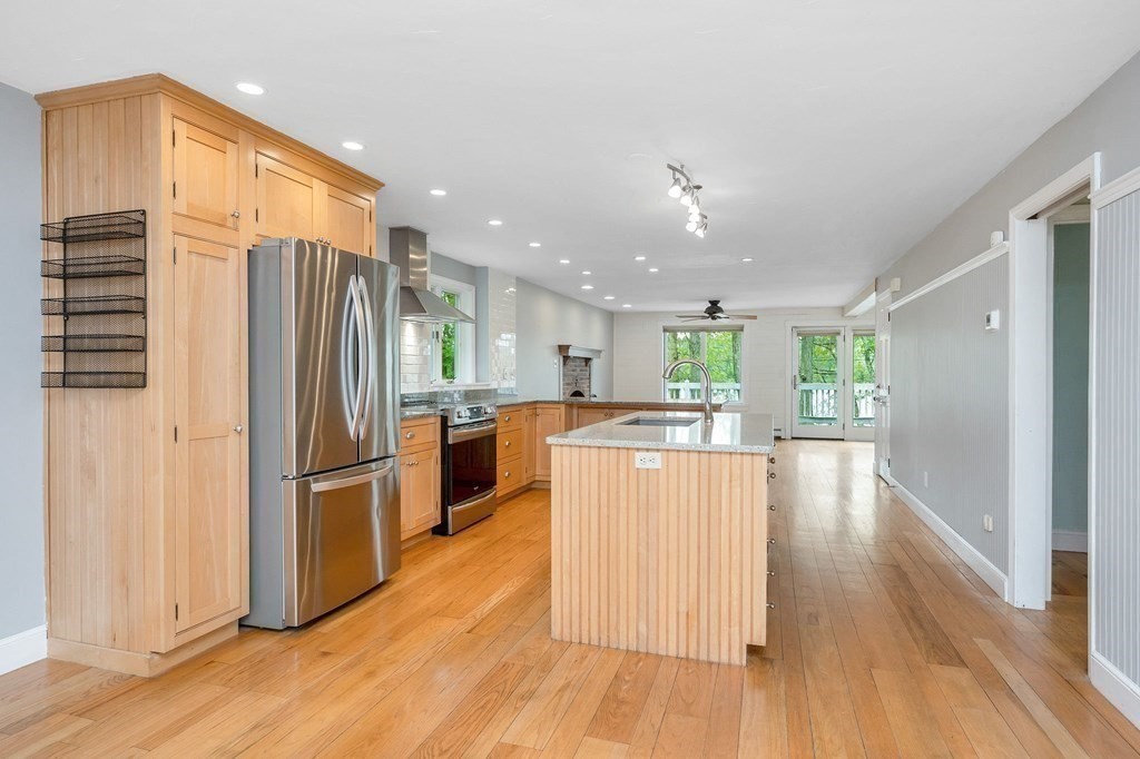 149 Pleasant Valley Road Amesbury, MA 01913 - Photo 7 of 42 a kitchen with stainless steel appliances kitchen island granite countertop a refrigerator a oven a stove and a wooden floors