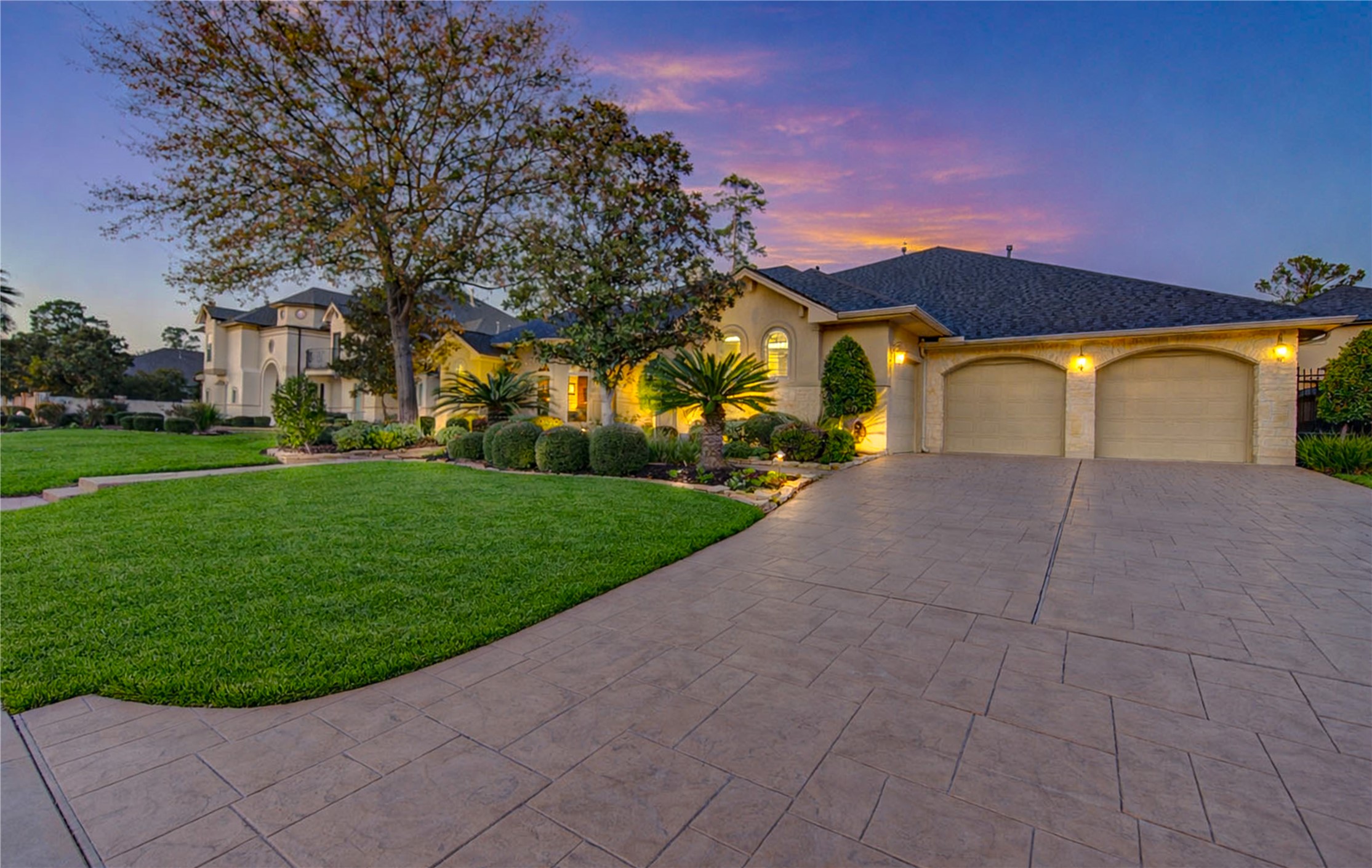 16618 Victoria Falls Lane Spring, TX 77379 - Photo 2 of 49 This photo showcases an elegant entryway with a decorative double door featuring intricate glass designs. The arched stone doorway complements the stucco exterior, and the surrounding windows add natural light. The tidy landscaping with bushes enhances the inviting atmosphere.