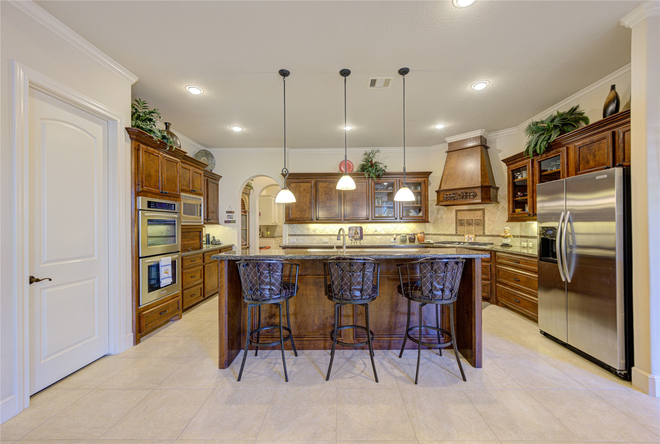 16618 Victoria Falls Lane Spring, TX 77379 - Photo 10 of 49 This kitchen features elegant wooden cabinetry, stainless steel appliances, and a central island with bar seating. It offers ample storage space and a warm, inviting atmosphere perfect for cooking and entertaining.