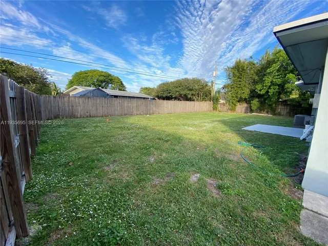 a view of a backyard with plants and large tree