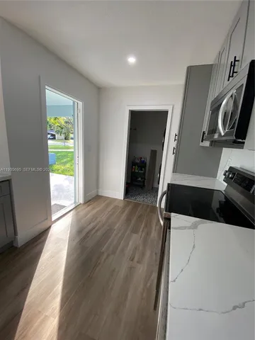a view of a kitchen with wooden floor and a refrigerator
