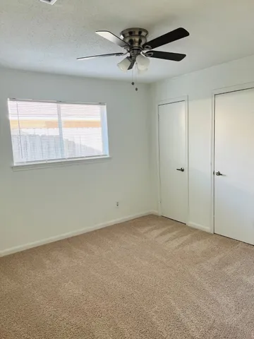 an empty room with a window and a fan