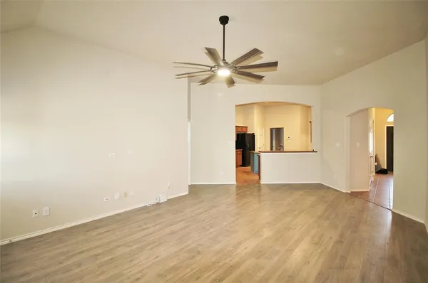 a view of empty room with wooden floor and ceiling fan