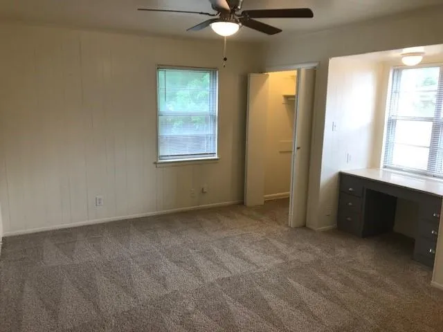 an empty room with windows and fan