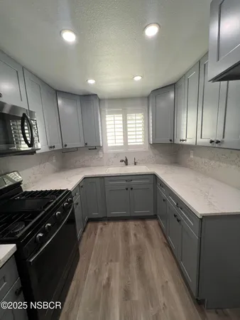 a kitchen with a sink a stove cabinets and a window