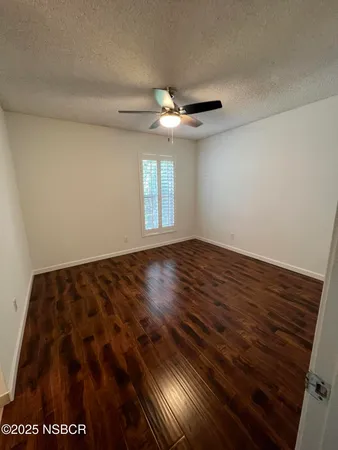 a view of an empty room with window and chandelier fan