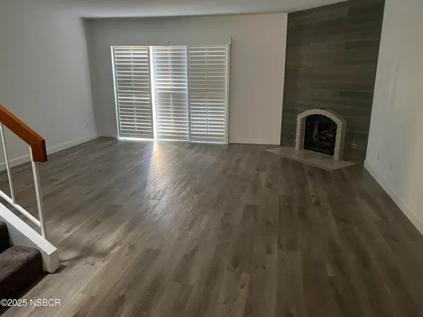 a view of empty room with wooden floor and fireplace