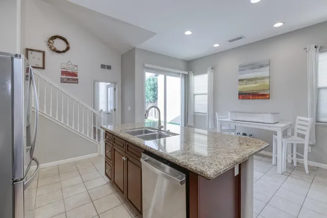 a kitchen with granite countertop a stove a sink and a refrigerator